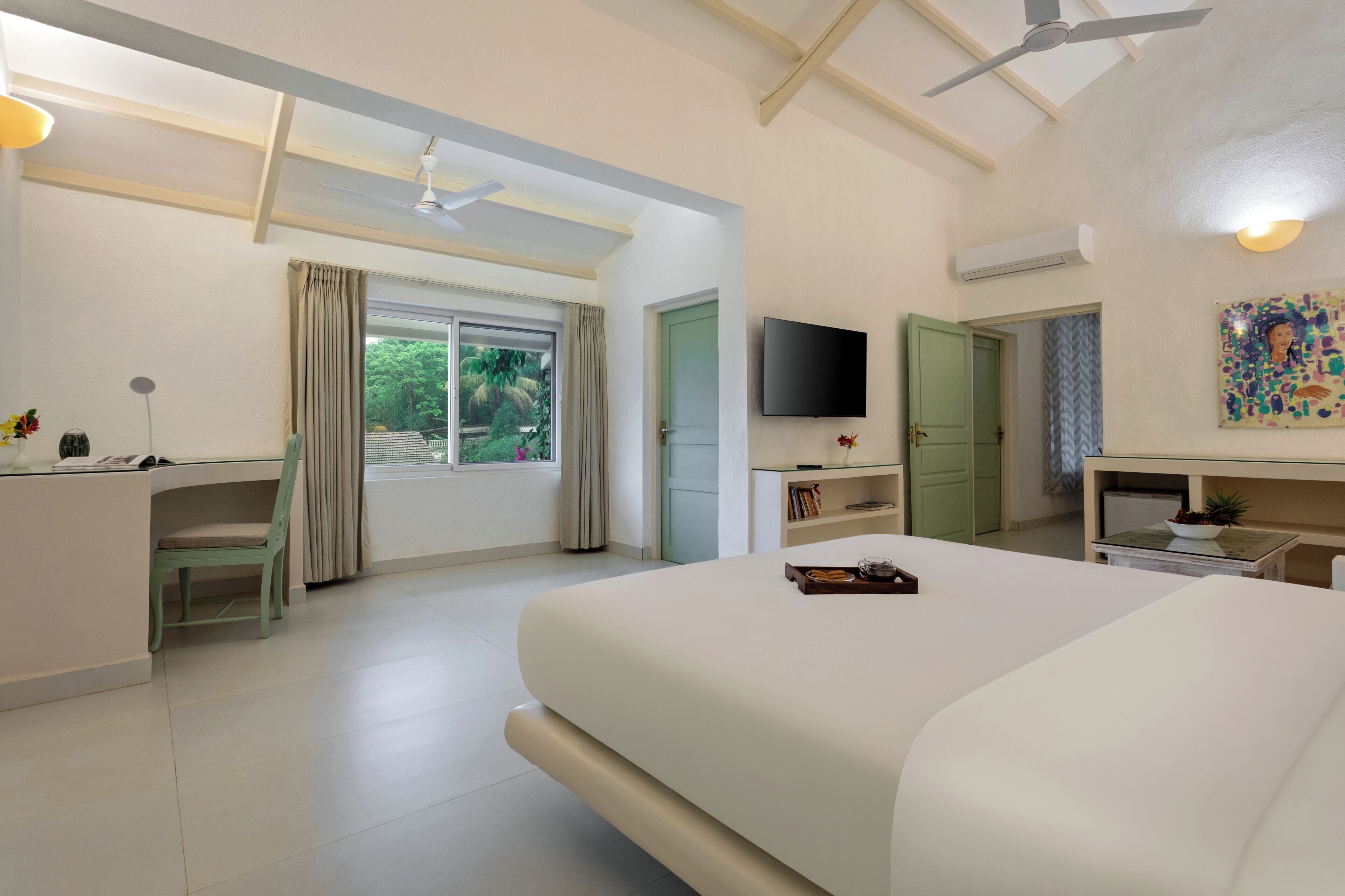 A hotel room with a bed, a desk, a chair, a television, and a window with curtains.