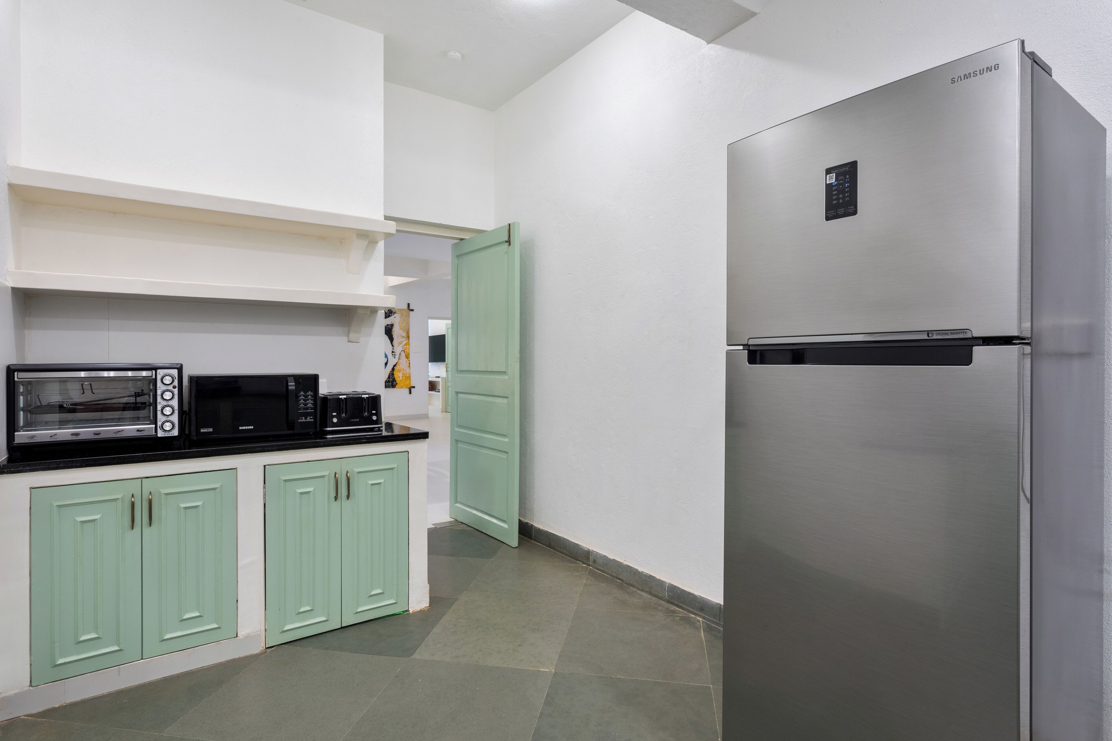 Una cocina con un refrigerador de acero inoxidable, un microondas y una tostadora.