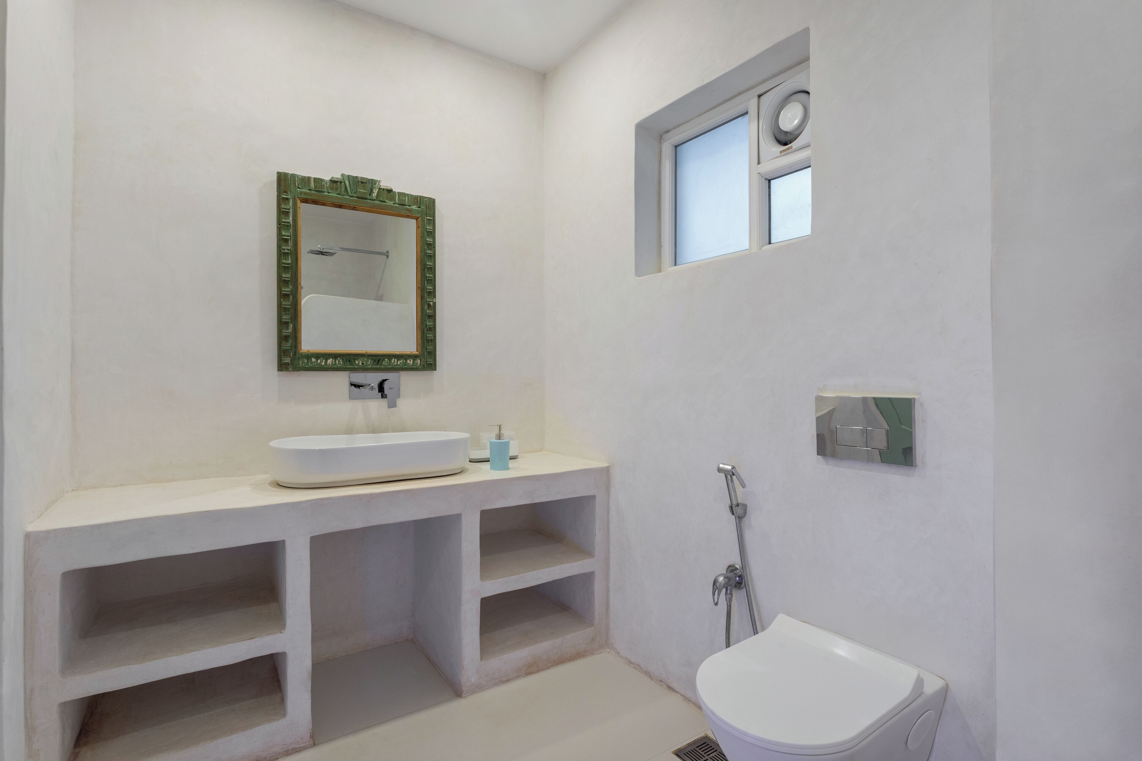 A bathroom with a white sink, a mirror with a green frame, a shower, and a toilet.
