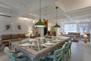 Un comedor amplio con una mesa larga dispuesta para cuatro personas, rodeado de sillas verdes.