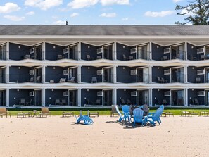 A multi-story hotel with balconies, outdoor seating, and a clear sky. - Beachfront, Heated Outdoor Pool, Jacuzzi Tub (Traverse City)