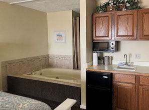 A bathroom with a bathtub, a shower, and a toilet. There is a sink with a microwave above it and a refrigerator below. - Beachfront, Heated Outdoor Pool, Jacuzzi Tub (Traverse City)