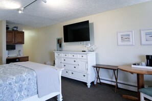 A hotel room with a bed, a dresser, a television, and a small table with a coffee maker. - Beachfront, Heated Outdoor Pool, Jacuzzi Tub (Traverse City)