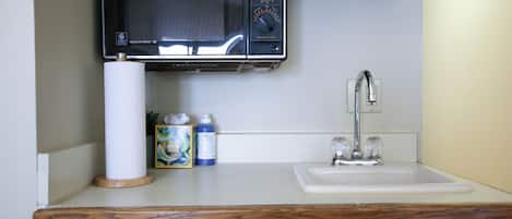 A kitchen with a microwave, a sink, and a dish soap bottle.