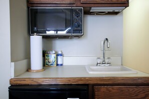 A kitchen with a microwave, a sink, and a dish soap bottle. - Beachfront, Heated Outdoor Pool, Jacuzzi Tub (Traverse City)