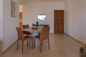 Een eethoek met een ronde tafel, vier stoelen, een vaas met planten en een houten deur.