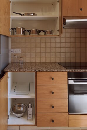 A kitchen with wooden cabinets, a stainless steel oven, and a granite countertop. - 160 LCA - Stay Sunshine City Apartment (Larnaca)