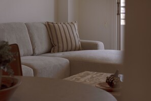 Een woonkamer met een bank, een kussen en een decoratief object op een tafel.