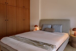 Een slaapkamer met een bed, nachtkastjes, een houten garderobe en een hoofdeinde.