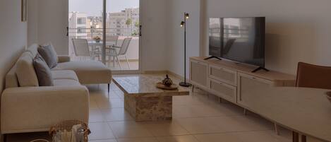 Una sala de estar moderna con un sofá, una mesa de centro, un televisor y un comedor.