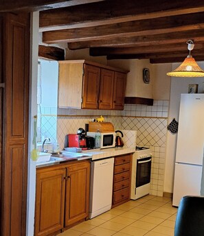 A kitchen with wooden cabinets, a microwave, a kettle, and a sink. - Charming country house on the outskirts of the Périgord (GAVAUDUN)