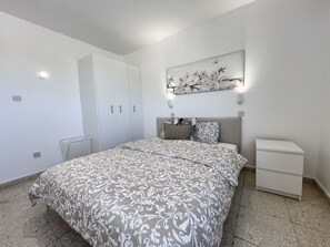 Ein Schlafzimmer mit einem Bett, einem Kleiderschrank, einem Nachttisch und einem Wandbild.