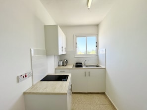 A compact kitchen with a built-in stove, a window, and a sink. - 161 AN - Stay Napa Zotiko Apartment (Ayia Napa)