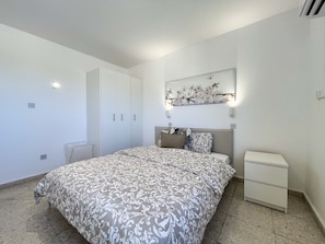 A bedroom with a bed, a wardrobe, a nightstand, and a wall-mounted light fixture. - 161 AN - Stay Napa Zotiko Apartment (Ayia Napa)