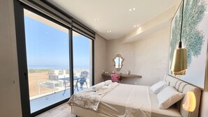 A bedroom with a bed, a desk, a chair, a large window with a view, and a hanging light fixture. - 155 PRO - Stay Prime View Apartment (Paralimni)