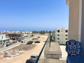 A balcony with a clear view of a coastal road, parked cars, and buildings in the background. - 155 PRO - Stay Prime View Apartment (Paralimni)