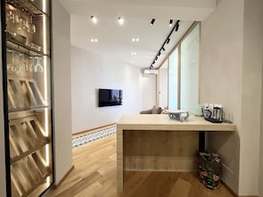 A modern kitchen with a wooden countertop, a built-in wine rack, and a flat-screen TV mounted on the wall. - 155 PRO - Stay Prime View Apartment (Paralimni)