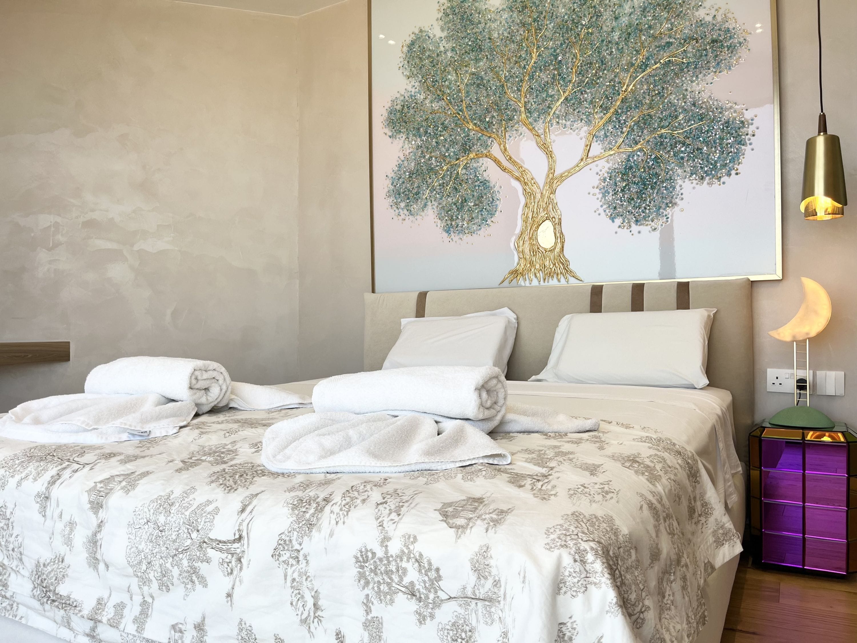 Una cama bien hecha con sábanas blancas y una colcha estampada con motivos florales.
