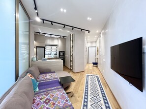 Una sala de estar moderna con un sofá, un tapete estampado y un televisor de pantalla plana montado en la pared.