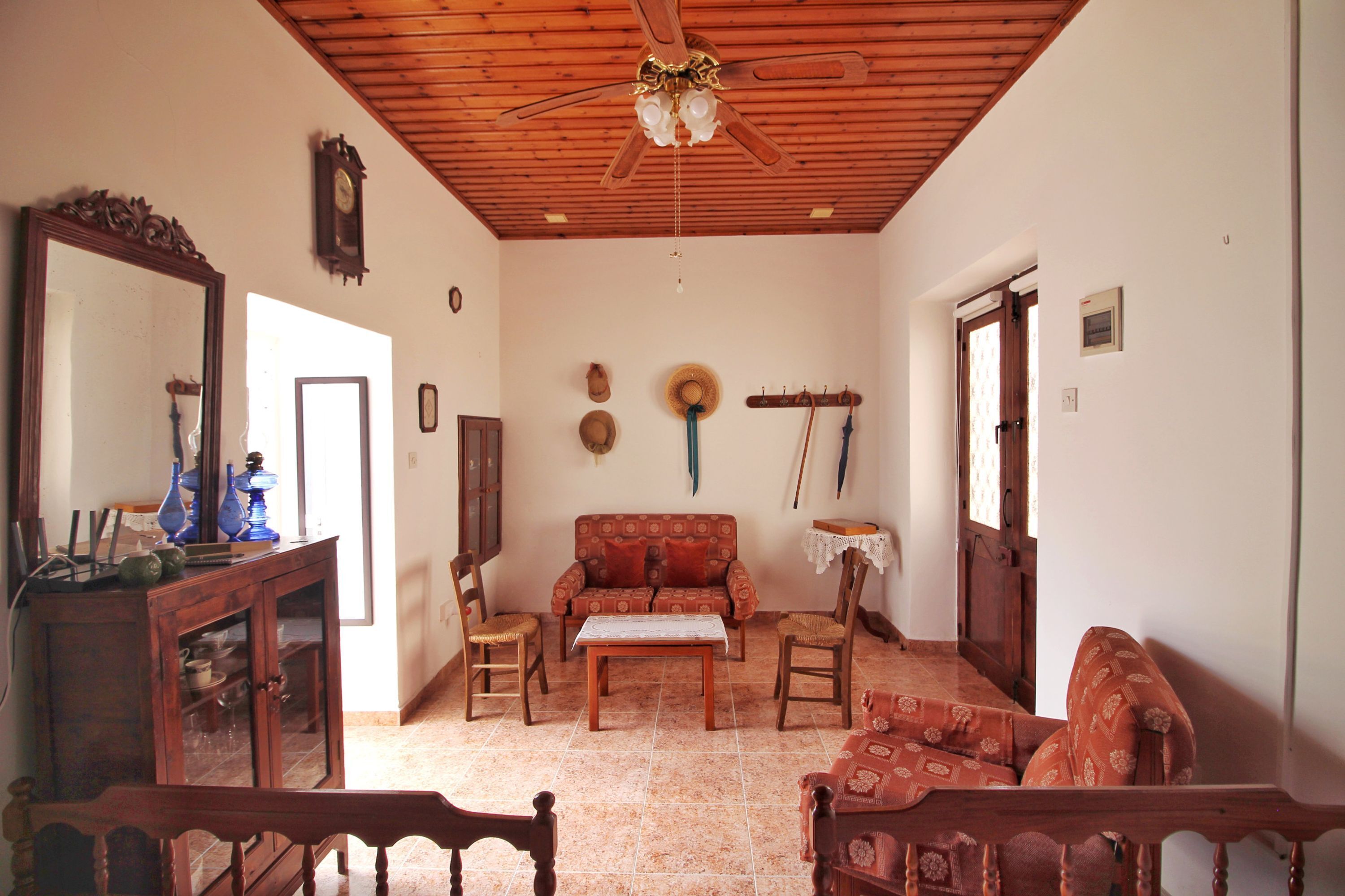 Une pièce avec un plafond en bois, un canapé, une table, des chaises, un miroir et un porte-chapeaux fixé au mur.