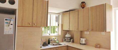 Una cocina moderna con armarios de madera, horno empotrado y refrigerador de acero inoxidable.