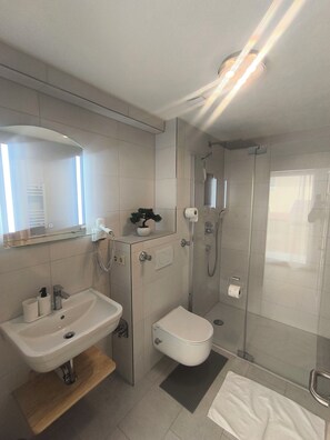 A modern bathroom with a sink, toilet, and glass-enclosed shower. - Vrbo Property (Reutlingen)