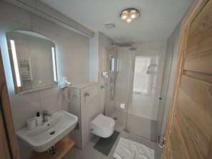 A modern bathroom with a glass-enclosed shower, a white sink, and a mirror above the sink. - Vrbo Property (Reutlingen)