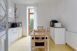 Cocina compacta con mesa, sillas, microondas y cafetera.