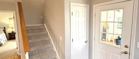 A staircase leading to a second floor, a white door with a window, and a wooden floor.