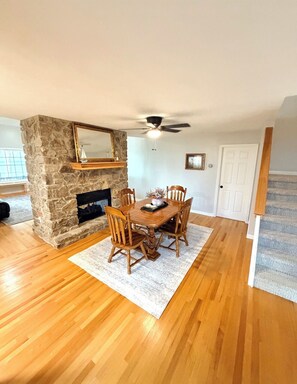 A dining area with a stone fireplace, wooden dining table, and chairs. - The Lookout at Lakeshore Estates (Hardin County)