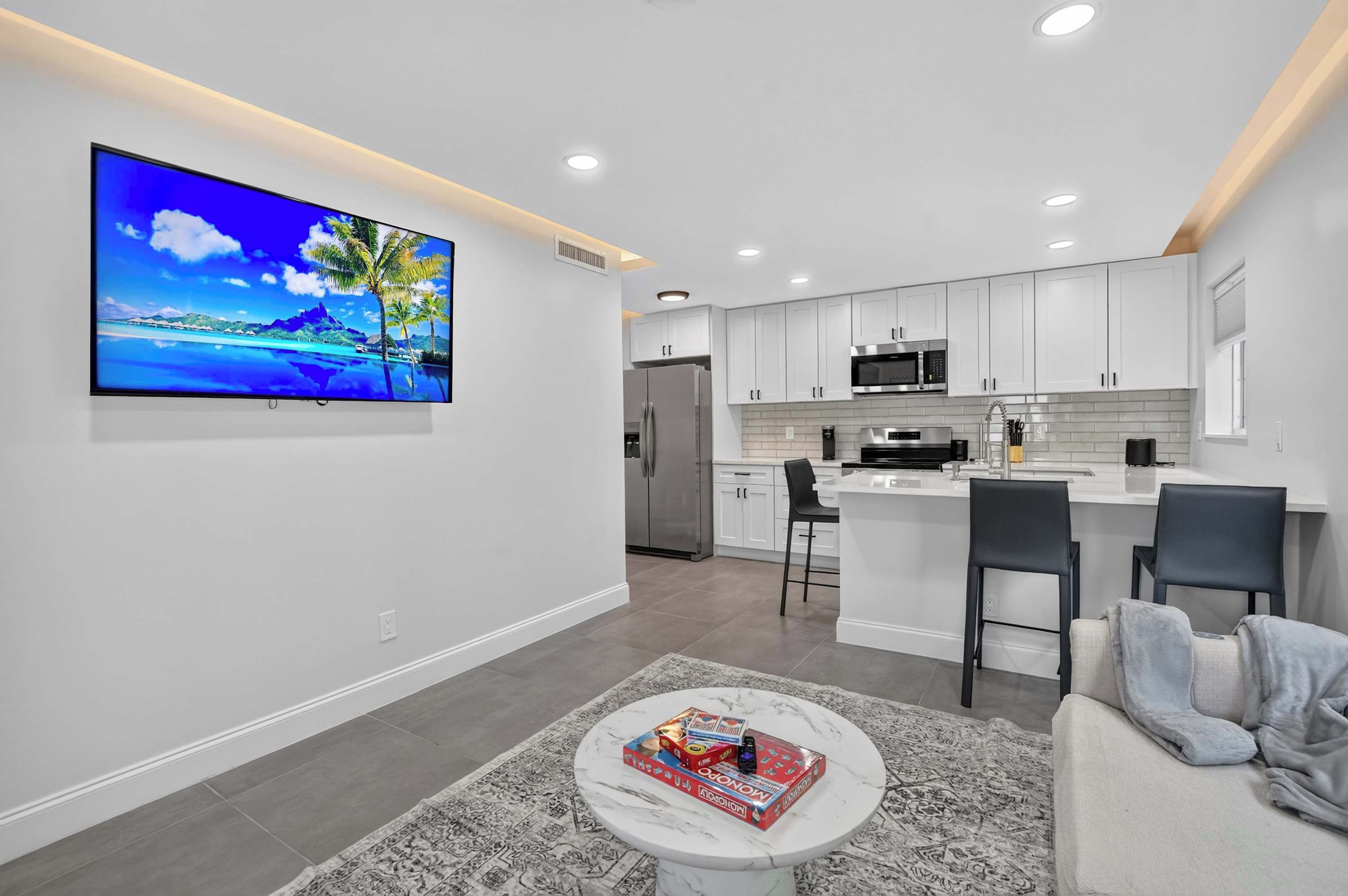 A modern kitchen with white cabinets, stainless steel appliances, and a central island with bar stools.