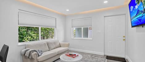 A modern living room with a beige sofa, a coffee table, and a television mounted on the wall.