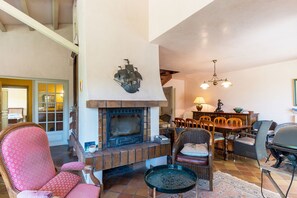 A spacious living room with a fireplace, a dining area with wooden furniture, and a staircase leading to an upper level. - Villa Occitane La Roche de Glun (La Roche-de-Glun)