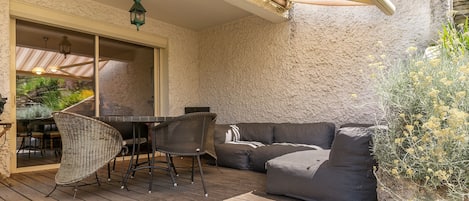 Un patio exterior con una mesa de comedor, sillas y un sofá.