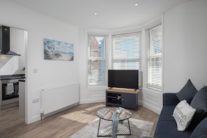 A modern living room with a TV, sofa, and artwork on the wall. - The Tide Apartments (Blackpool)