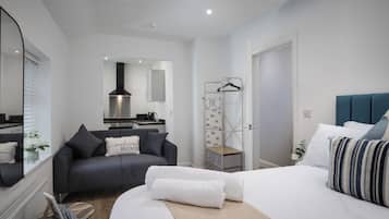 Un dormitorio moderno con cama, sofá, armario y kitchenette.