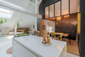 A modern interior with a central island table, seating area, and a large window with a view. - The White Forest - Proche Epinal (Thaon-les-Vosges)