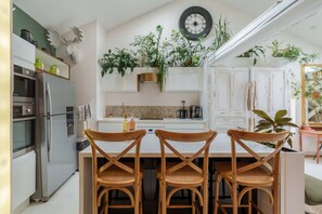 A modern kitchen with a central island, stainless steel appliances, and wooden chairs. - The White Forest - Proche Epinal (Thaon-les-Vosges)