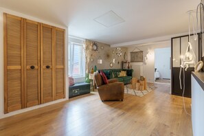 Un vaste espace de vie doté d’un plancher en bois, d’un canapé vert et d’un fauteuil marron.