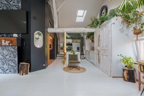 A modern interior with a central seating area, a kitchen with white cabinets, and a dining area with a wooden table. - The White Forest - Proche Epinal (Thaon-les-Vosges)