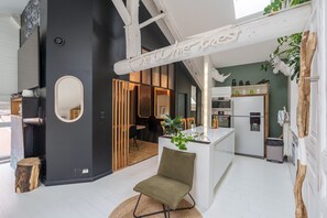Un intérieur moderne comprenant un coin repas, une cuisine et un grand miroir.