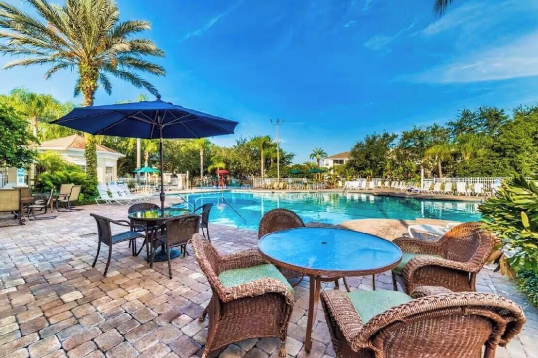 A poolside area with wicker furniture and a large umbrella.