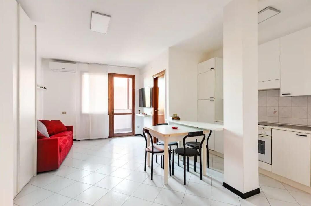 Un appartamento moderno con zona pranzo, cucina e un divano rosso.