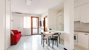 Un appartamento moderno con zona pranzo, cucina e un divano rosso.