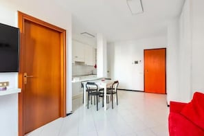 Eine moderne Wohnung mit Essbereich, Küche und einem roten Sofa.