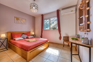 Una camera da letto con un letto in legno, un comodino con una lampada, una finestra con tende e un condizionatore d'aria a parete.