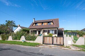 A two-story house with a sloped roof, a front porch, and a fenced yard. - Beach house Sainte-Cécile - Avec beau jardin (Camiers)