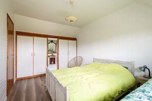 A bedroom with a bed, a nightstand, a lamp, a wardrobe, and a mirror. - Beach house Sainte-Cécile - Avec beau jardin (Camiers)