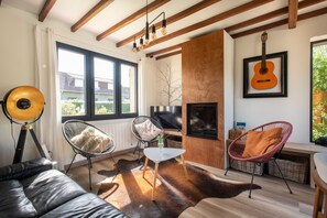 A modern living room with a sofa, chairs, a fireplace, and a guitar on the wall. - Beach house Sainte-Cécile - Avec beau jardin (Camiers)