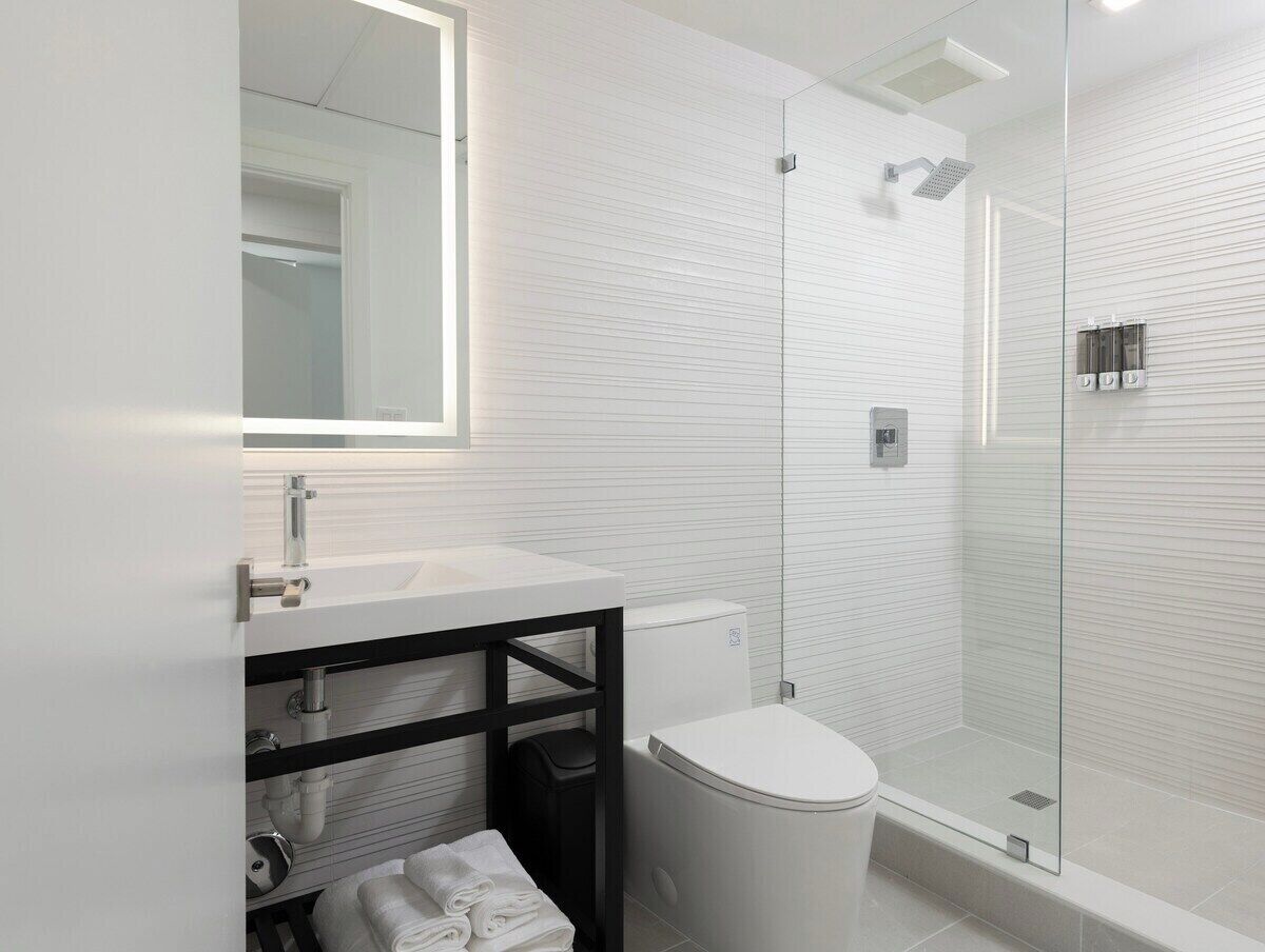 A modern bathroom with a white sink, toilet, and glass-enclosed shower.